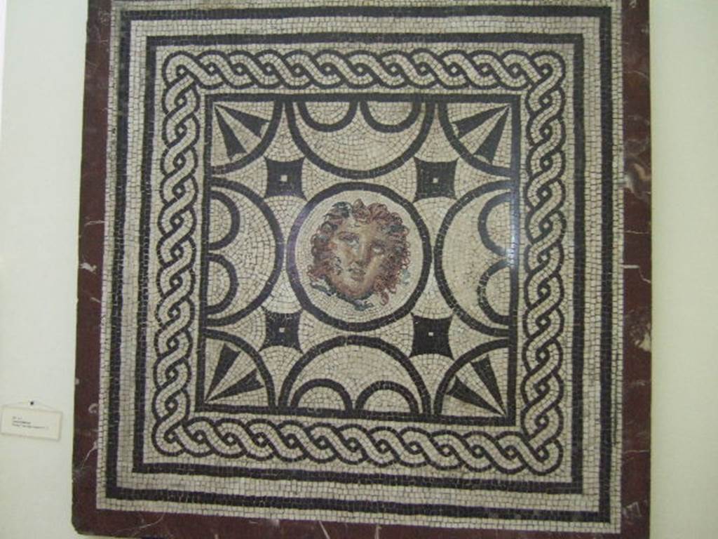 Found in VI.1.7 Pompeii. Mosaic with head of Medusa.
Now in Naples Archaeological Museum. Inventory number s. n.
According to Pagano and Prisciandaro –
11 Novembre 1784, Cubicolo –
“Si continua a scavare nella consaputa abitazione, e si e scoperta una stanza. Questa tiene il pavimento di musaico bianco, ed il piano suo vien distinto da un grado alto on.6. Tale altezza e ornata da un fascia di marmo, ed il detto piano superiore e di musaico liscio. E nel piano sottoposto vi e un quadro con dei lavori di musaico nero, e nel centro vi e una testa bellissima di Medusa anche di musaico. Le mura di questa stanza sono cosi dipinte: lo zoccolo giallo con alcuni lavori, il dippiu bianco con riquadrature di fasce rosse con varie pitture, festoni ed altro. Vi si e trovato – Bronzo: Una lucerna ad un luminello e suo manico. Un piccolo anelletto. Due chiodi ed una centrella. Osso: Un netta orecchie.”
See Pagano, M. and Prisciandaro, R., 2006. Studio sulle provenienze degli oggetti rinvenuti negli scavi borbonici del regno di Napoli. Naples: Nicola Longobardi. (p.82 and see PAH,1,2,24 and Addendum p.40 (Il mosaico fu tagliato il 13 Decembre 1787).
(translation – 11th November 1784, Cubiculum –
"We continued to dig in the known house and found a room.
This room had a white mosaic floor, and the floor was distinguished by a high step of 0.13m (approx. 5 inches high).
This height was decorated by a strip of marble, and the said upper part of the floor was of smooth mosaic.
And in the floor below, there was a picture worked with black mosaic, and in the middle there was a beautiful head of Medusa, also in mosaic.
The walls of this room were painted: with a yellow zoccolo, with panels separated by red bands with various paintings, garlands and more.
Bronze and bone items were found."
(Addendum: the mosaic was cut and taken to the Museum on 13th December 1787). (see below – sent on 21st December 1787).
PAH, 1787, p.40 –
13th Decembre 1787.
Si e mandato ad avvisare a Canart, che mandi a tagliere li due quadri di musaico, secondo ordino il sig. Ajutante D. Pietro La Vega.
Uno e quello con la testa di Medusa di pal 3 ed on.8 in quadro; l’altro e quello con lo scheletro, che tiene in ciascuna mano, un vaso con la bocca inclinata verso la terra, di pal. 2 ¾ per pal. 2 ed on.5.
21st Decembre 1787.
Si sono mandati questa mattina pel R. Museo a D. Giuseppe Canart i due quadri di musaico, notati nel passato rapporto.
(translation - 13th December 1787.
One has sent to advise Canart to cut the two mosaics, according to the orders of La Vega. One is the one with the head of Medusa of 0.97m squared;
the other that with the skeleton holding a vase in each hand with the mouth tilted towards the earth, 0.73m x 0.64m.
21st December 1787.
This morning, one has sent the two squares of mosaics, noted in the past report to the Royal Museum to D. Giuseppe Canart.)
(Note – the mosaic of the skeleton with the vase in each hand was excavated from VI. Ins. Occ. 25).