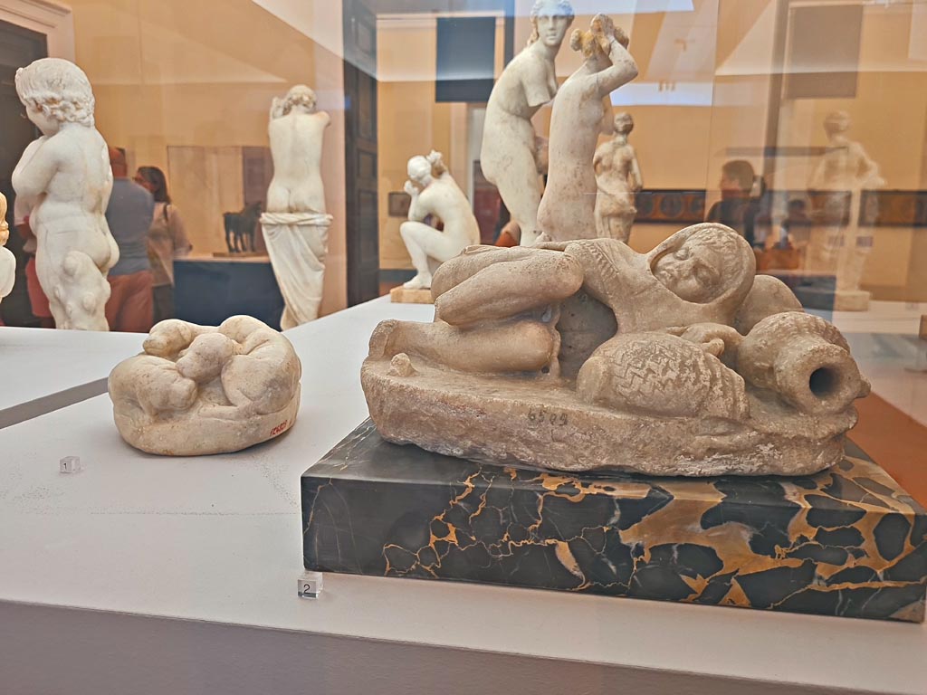 VI.8.23 Pompeii. October 2023.
Marble statuette of a small sleeping fisherman, on right, found in the garden area at the side of the nymphaeum, inv. 6509.
On the left, marble block modelled into four puppies, found near small stairs in room 17 of VI.12.2/5 on 21/5/1895, inv. 124829.
Photo courtesy of Giuseppe Ciaramella.
On display in “L’altra MANN” exhibition, October 2023, at Naples Archaeological Museum.