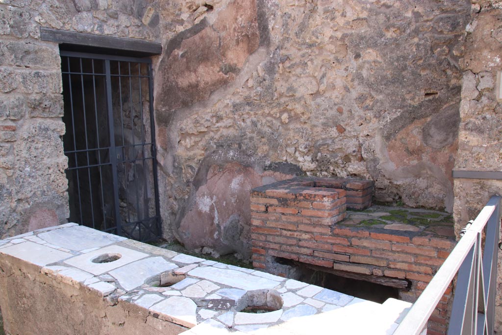 VI.10.1 Pompeii. March 2009.  South wall of caupona with hearth and doorway to rear room on south side. According to Eschebach, the stairs to the upper floor would have been against this south wall. Where the modern gate has been fitted, there may be a mark showing the steps leading up the wall.
