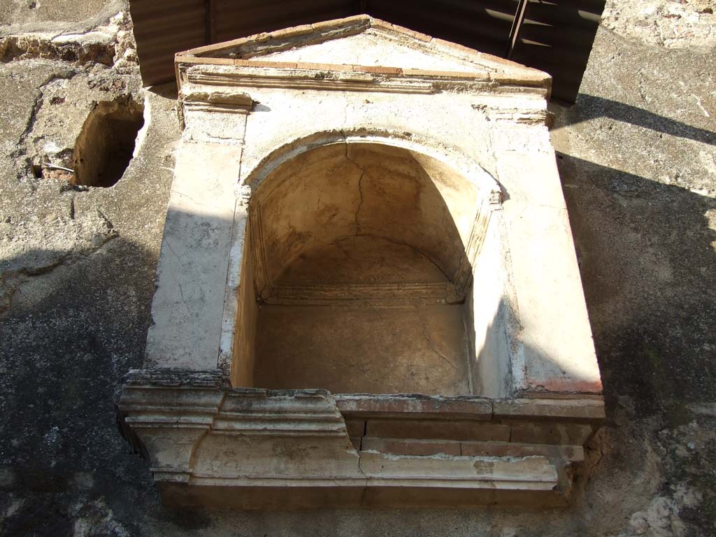 VI.12.2 Pompeii. December 2006. North wall of Kitchen, arched niche lararium with aedicula façade.
According to Boyce, there was a heavy and well-made aedicula façade with two red pilasters supporting a simple pediment.
Inside the niche and around the curve was a modelled stucco cornice.
Within the niche there stood a small terracotta altar.
See Boyce G. K., 1937. Corpus of the Lararia of Pompeii. Rome: MAAR 14. (p.52, 190, Pl. 5, 2).
(PPM – room 24)