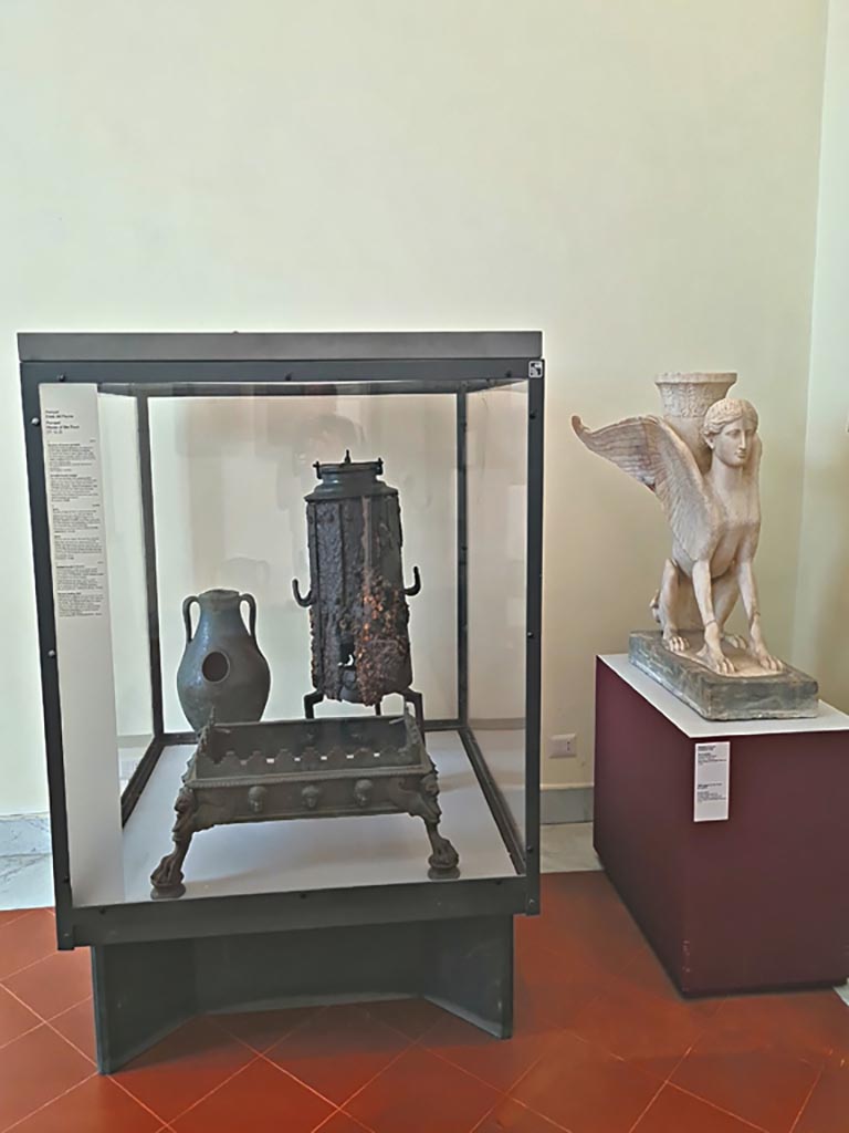VI.12.2 Pompeii. September 2024.
Display case with items – Portable bronze brazier, Stove and bronze chafing dish.
Now in Naples Archaeological Museum. Photo courtesy of Giuseppe Ciaramella.