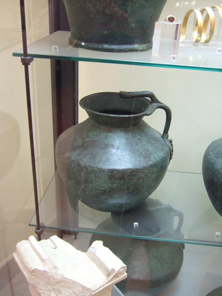 VI.12.2 Pompeii. One handled bronze jug, with small limestone altar, below.
Now in Naples Archaeological Museum. Inventory number 69425.
The small altar (second half of the 2nd century BC), found 1831, now in Naples Archaeological Museum. Inv. 2550 (Vetter 21), with Oscan inscription, written from right to left, reading –
“To flora”
(Piccola ara (seconda metà del II secolo a.C.), trovato 1831, inv. 2550 (Vetter 21), alfabeto osco, scrittura da destra verso sinistra –
“A Flora”)
According to the information card in Naples Museum –
“Flora is one of the minor deities connected to the regenerative cycles of nature. Her cult was diffused through the Italic world, and is attested in Rome as well”.
(“Flora è una delle divinità minori legate ai cicli rigenerativi della natura, il cui culto era diffuso nel mondo italico e si ritrova anche a Roma.”)