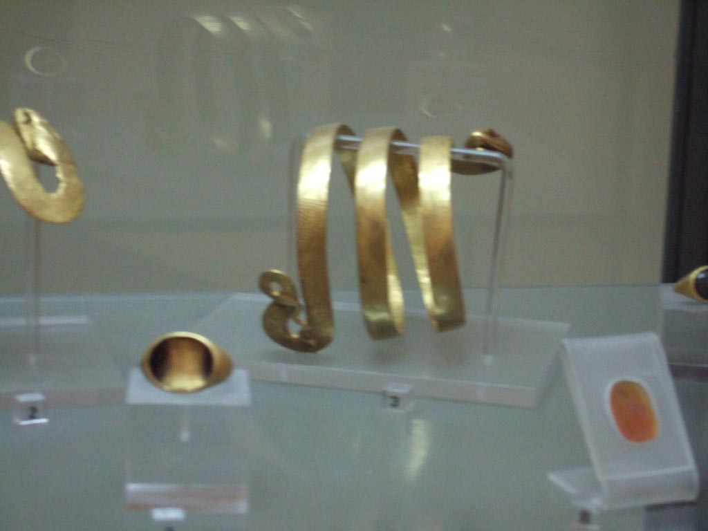 VI.12.2 Pompeii. Found 4th March 1831. Gold bracelet with body of a serpent (at back). Inventory number 24825.
Gold ring (on left). Inventory number 25107.
Carving on cornelian of bust of a youth, possible Alexander the Great (on right). Inventory number 26766.
Now in Naples Archaeological Museum.