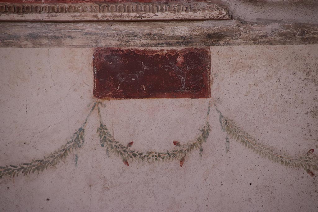 VI.15.1 Pompeii. October 2024.
Small painted panel at north end of west wall of oecus. Photo courtesy of Klaus Heese.