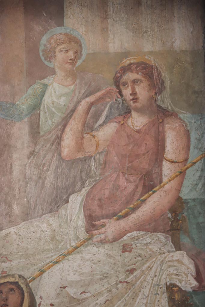 VI.15.1 Pompeii. October 2023. Detail of Juno and long stick/baton against right arm. 
Hera/Juno with gold crown and long sceptre is seated on her throne with Iris standing to her left, gesticulating.
Photo courtesy of Klaus Heese.
