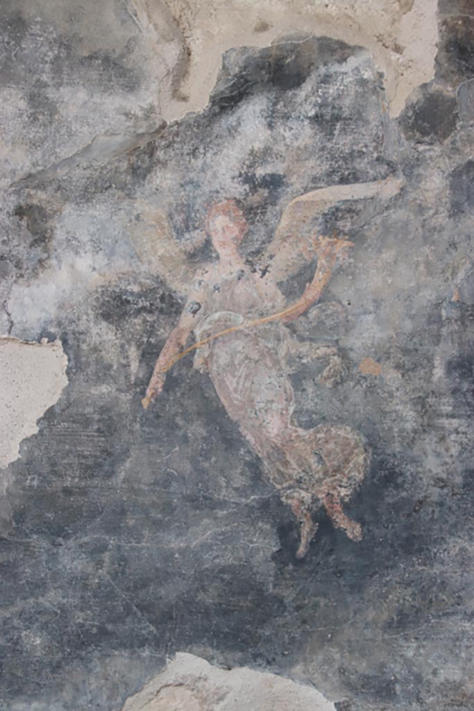 VI.15.1 Pompeii. October 2023.
Painting of winged figure with cornucopia, from west wall of peristyle towards north end.
Photo courtesy of Klaus Heese.
