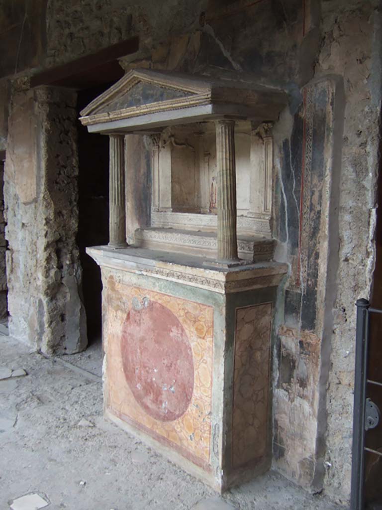 VI.16.7 Pompeii. May 2006. Room F, north portico. Household lararium.
According to Boyce, the shrine was found with its contents intact, and contained the following bronze statuettes:
1. Jupiter – bearded, the upper part of his body nude, the lower part wrapped in a robe. In his right hand the thunderbolt, in the left he probably originally held a sceptre, now missing.
2. Juno – wearing a peplum fastened on her right shoulder and over it a mantle, on her head a high crown.
3. Minerva – wearing a peplum and mantle and on her breast the gorgon, on her head a helmet.
Also found were a statue of Mercury, and the Two Lares.
See Boyce G. K., 1937. Corpus of the Lararia of Pompeii. Rome: MAAR 14, pp. 57-8, no. 221, and pl.38, 2.