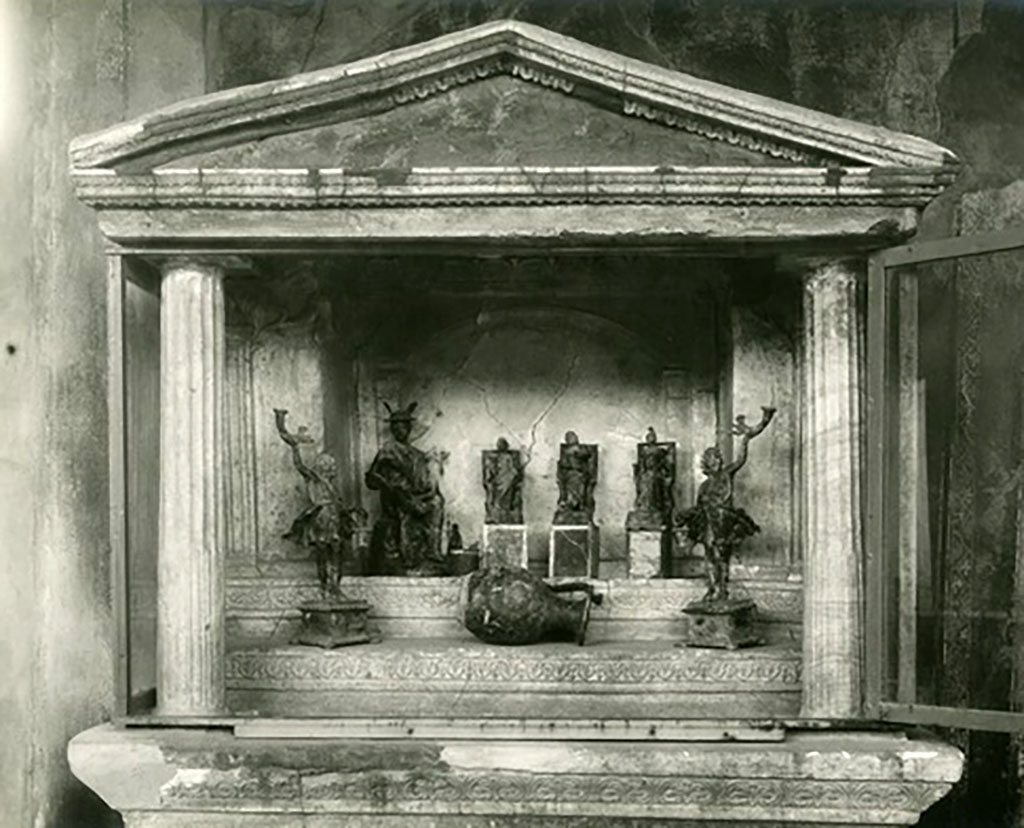 VI.16.7 Pompeii. Statues found in the lararium.
Seated on the top step are Mercury, Juno, Jupiter and Minerva.
The two Lares were placed, on either side of the group, but on the lower step.
Also found was a bronze vase in the shape of an oinochoe with a large belly, flat bottom, protruding lip and a handle set laterally to this.
Now in Naples Archaeological Museum. Inventory numbers 133323, 133324, 133325, 133327, 133328 (and 133326?).
See Boyce G. K., 1937. Corpus of the Lararia of Pompeii. Rome: MAAR 14, pp. 57-8, no. 221, and pl.38, 2.
See Notizie degli Scavi di Antichità, 1907, pp. 564-571, fig. 14.