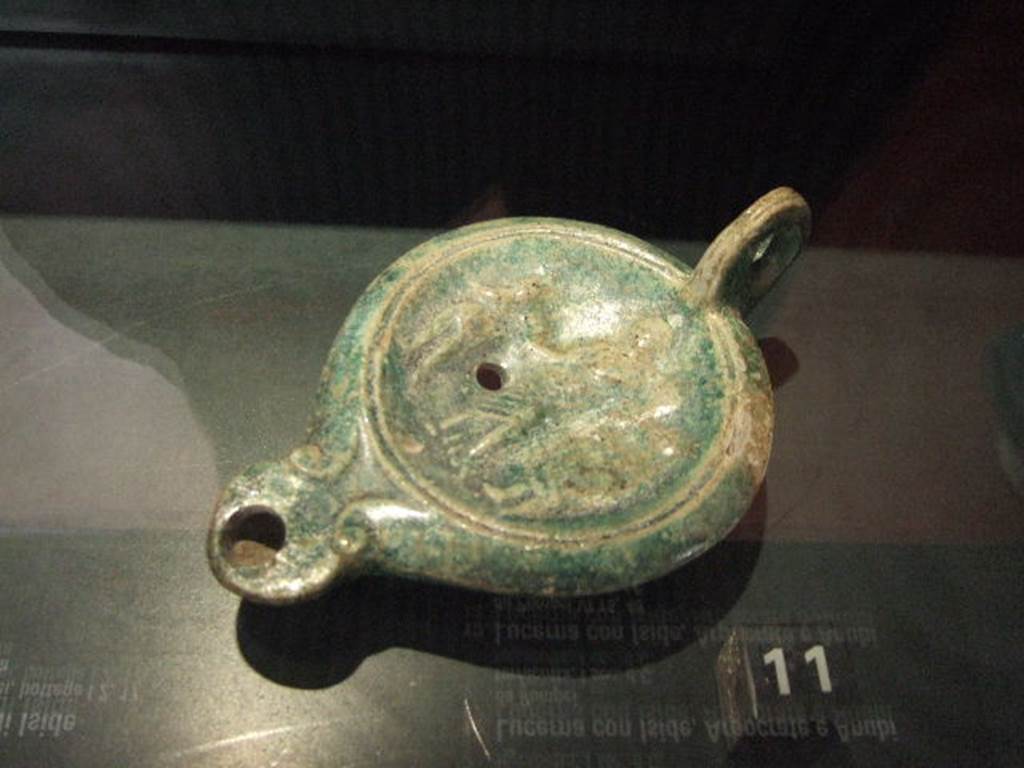 VI.16.7 Pompeii. Found in the corner near the lararium in room F, peristyle.
Terracotta lamp with images of Isis, Harpocrates and Anubis.
Now in Naples Archaeological Museum. See Engelmann, W., 1929. New Guide to Pompeii: Second Edition. Engelmann. (p. 52).