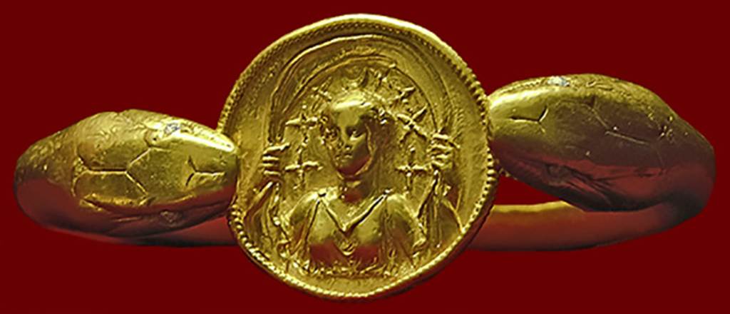 VI.17.42 Pompeii. Golden bracelet found on the arm of a woman.
According to Barbara McManus, this remarkable bracelet, 610 grams (21.5 oz) of solid gold, is fashioned in the form of two snakes flanking a round disk with a carved relief of Selene with crescent moon and stars above her head.
It was found on the arm of a woman carrying a casket containing 40 aurei and 180 denarii.
She was killed along with another adult and a child when a balcony collapsed in the house.
Photo courtesy of Barbara McManus. See The VRoma Project
Now in Naples Archaeological Museum. Inventory number 14268.