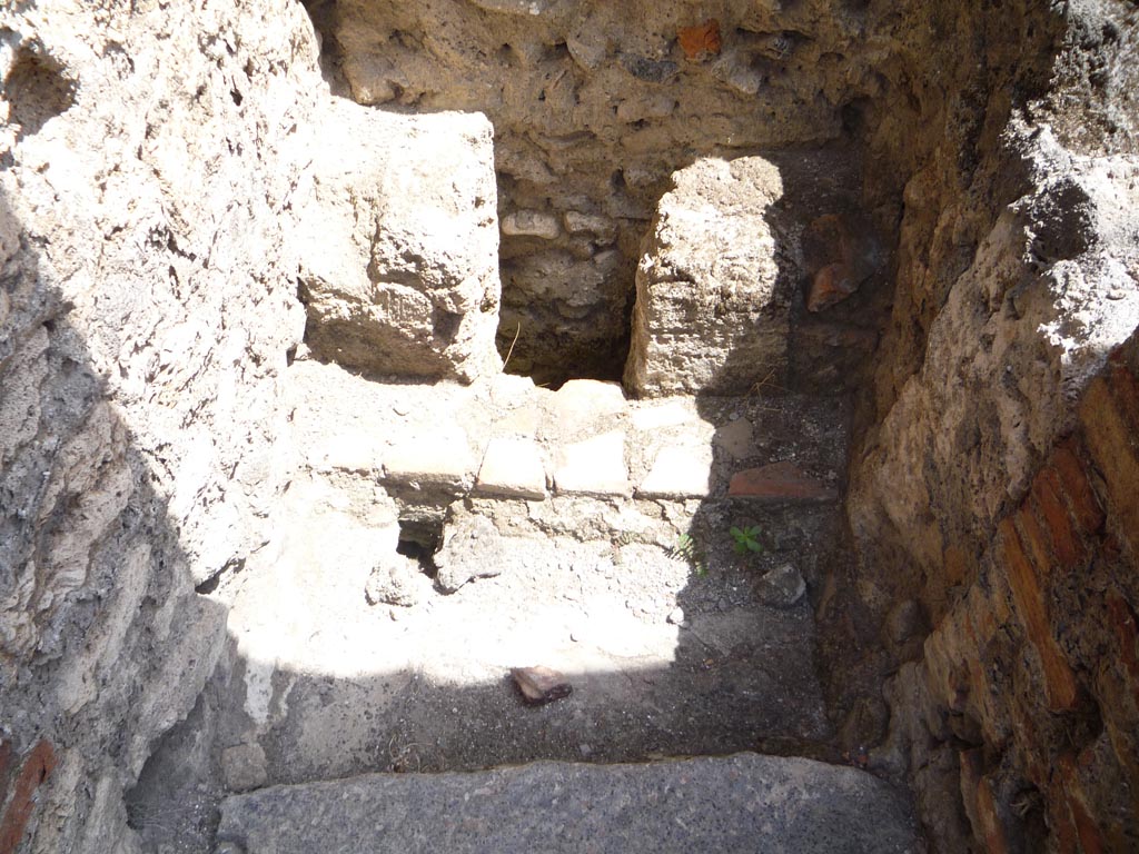 VII.1.36 Pompeii. October 2009. Looking east into latrine. Photo courtesy of Jared Benton.
According to Hobson, the workers on the ground floor still required a latrine.
This small room was constructed encroaching onto the property on the eastern side (VII.1.30).
The pedestals had a foot-rest in front of them with a tiled floor into which a rectangular drain was inserted.
A threshold stone had only one pivot hole and the door could not have opened outwards because the stones in the bakery were higher than the threshold.
Perhaps the door folded?
See Hobson, B., 2009. Latrinae et foricae: Toilets in the Roman World. London; Duckworth. (p.53, figs. 71 and 72).
