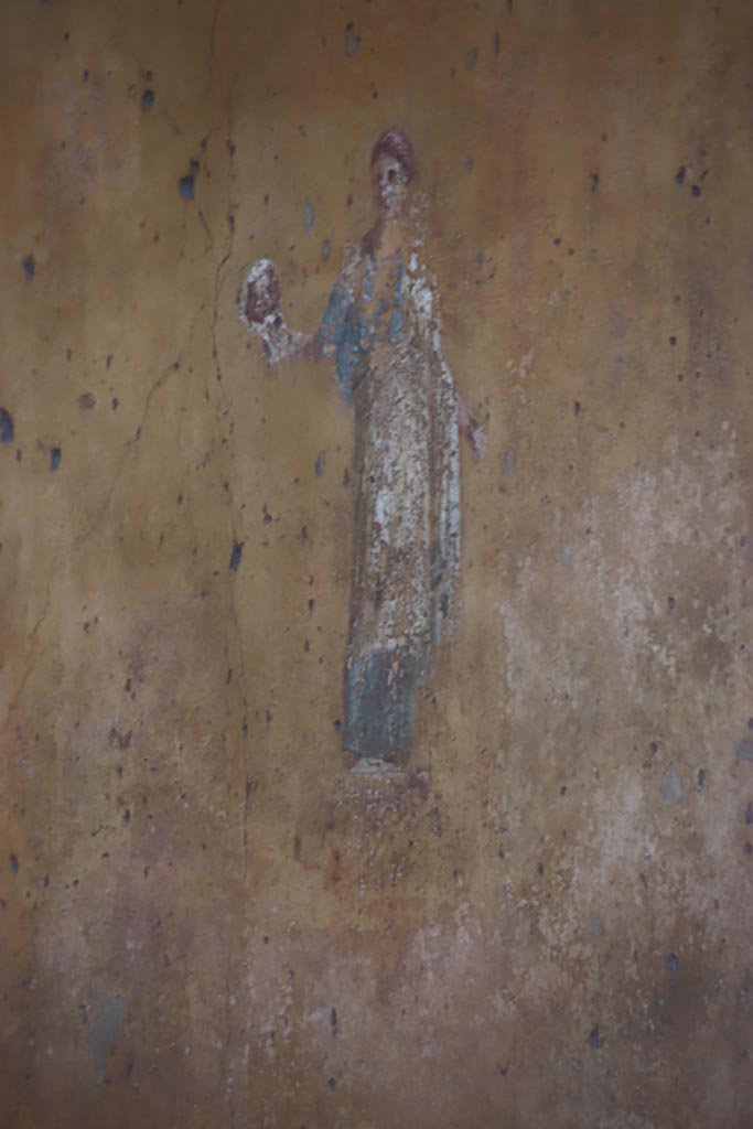 VII.1.47 Pompeii. October 2023.
Exedra 10, Muse Thalia from north (left) yellow panel on the east wall. Photo courtesy of Klaus Heese.