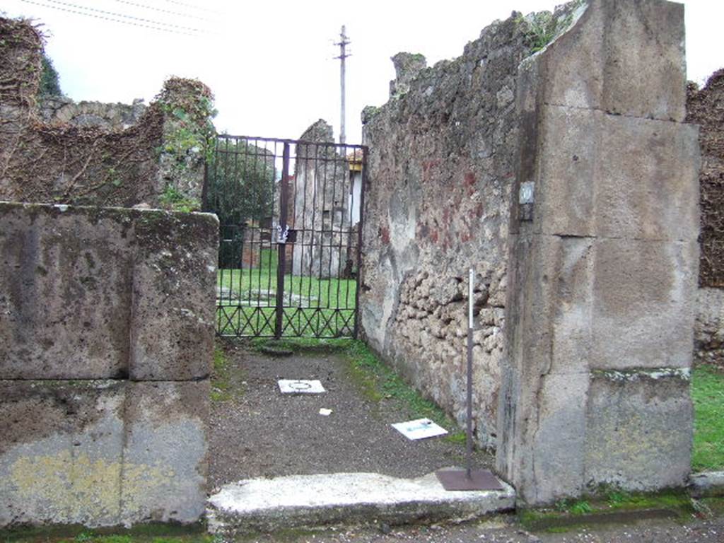 VII.4.59 Pompeii. December 2005. Entrance c and fauces d to the House of the Black Wall.The house was named after the exedra or triclinium y discovered with painted IV style black walls. Due to the bombing in the night of 13th September 1943, much damage was done. The IV style stucco and plaster in the cubicula near the atrium was lost. In the peristyle, the plaster on the columns and the paintings on the walls were damaged, and the east wall was partly demolished. Worst of all was the damage to part of the famous IV style triclinium. When excavated the triclinium had been found missing most of the decoration on its east side. After the bombing, most of the west side was lost as well. The south wall was partially destroyed. Many interesting small paintings were destroyed.
The walls of this triclinium were restored in the following years from many fragments. Partial restoration was also completed in the atrium and peristyle.
See Garcia y Garcia, L., 2006. Danni di guerra a Pompei. Rome: L’Erma di Bretschneider. (p.101)