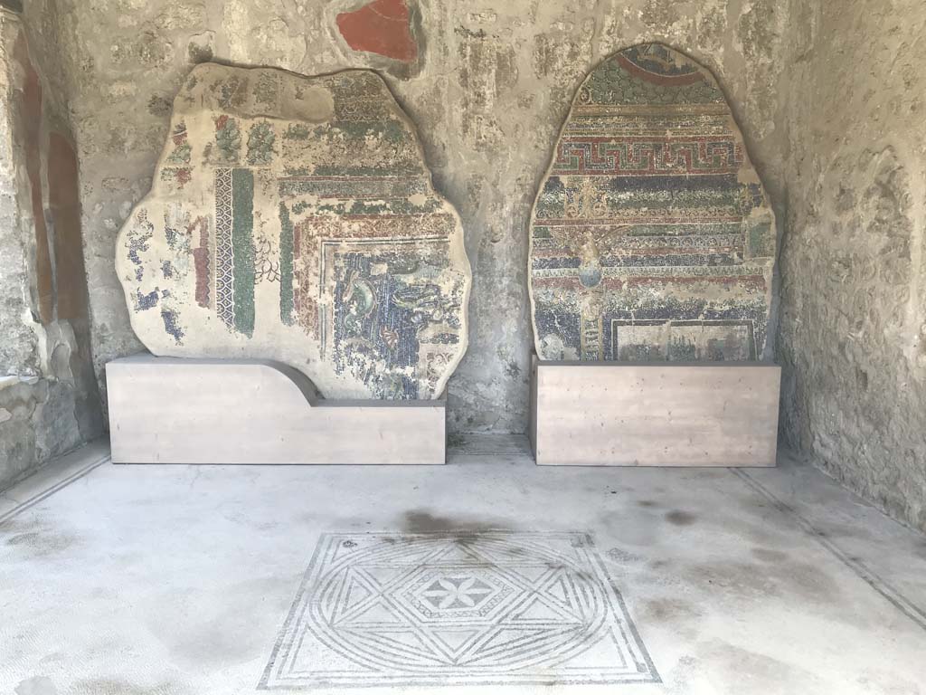 VII.7.5 Pompeii, April 2019. Room (n), looking across mosaic flooring towards east wall.
On the left, north wall, is a window from south portico of linked house at VII.7.2.
The mosaics leaning against the west wall do not come from this house, but are from the nearby Suburban Baths near the Porta Marina. Photo courtesy of Rick Bauer.
