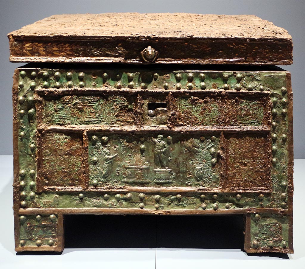 VII.7.5 Pompeii, Found 29 October 1864, now in Naples, Museo Archeologico Nazionale, (inv. 73020).
“Arca”/strong-box with Sacrifice to Jupiter, after restoration, made of wood, with iron and bronze coating; copper bronze and tin.
Photo “Restituzioni 2016” courtesy of Sailko, <CC BY 3.0>, via Wikimedia Commons.
The strong-box/safe with an offering to Jupiter was discovered in Pompeii on 29 October 1864 in the House of Triptolemus (VII.7.5)
According to Fiorelli –
…ed immette nell’atrio tuscanico, ove la cassa di ferro pel domestico peculio stava situata sopra un grande pezzo di travertino, ch’e a sinistra della porta d’ingresso: delle sue dipinture rimangono sei Amorini, tutti portanti in mano un corno d’abbondanza.
(trans: “and leads into the Tuscan atrium, where the iron chest for domestic money was placed on a large piece of travertine, which is on the left of the entrance doorway: of its paintings (in the atrium) remain six Cupids, all carrying in their hand a horn of abundance.”)
See Pappalardo, U., 2001. La Descrizione di Pompei per Giuseppe Fiorelli (1875). Napoli: Massa Editore. (p.98)
See Fiorelli, G., 1875. Descrizione di Pompei. Napoli, (p.242).