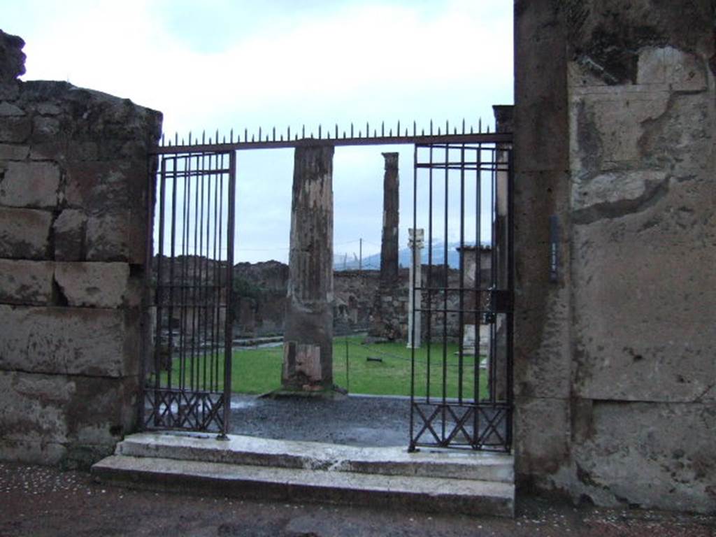 VII.7.32 Pompeii. December 2005. Entrance doorway on Via Marina.
According to Cooke Cockburn and Donaldson: “However splendid in their general arrangements, the columns of the peribolus are capricious in taste and decoration. The capitals are of stucco, of the Corinthian order, with a single row of leaves covering a capital originally Doric; the entablature is of tufo, once Doric, but converted to accord with the capital by a thick coat of plaster, in a grotesque style and painted. The walls of the court are covered with paintings of the most interesting description. They are in vivid colours and represent generally landscapes, views of country houses, interiors of rooms with male and female figures; in several compositions figures are drawn sporting among themselves, sacrificing to Priapus, contending with crocodiles, or occupied in domestic duties; nor must we omit a painting of Hector tied to the car of Achilles, and one of Agamemnon and Achilles. The sanctuary itself now presents only its four dark walls, raised on an elevated and dismantled basement, in former times enriched with marbles; the portico completely surrounded the cella, having six columns in front, and in all probability eleven on the flanks, agreeing in this respect with the rules of Vitruvius.
Withinside is the rough construction for the altar, and the pavement is a very elegant mosaic, the centre compartment consisting of green, white and black marbles, and the border of a Greek meander of black, white and red mosaic. The walls, as well as the steps, retain every appearance of the fatal effects of the earthquake, being shattered, out of level, and displaced. At the end of the court, opposite the entrance, is a small chamber, which possesses an invaluable picture of Bacchus and Silenus, the former holding the thyrsus in one hand and a vase in the other; Silenus appears with his lyre instructing the god. A small niche is in the wall, apparently for the reception of a statue or lares.”
See Cooke Cockburn Donaldson: Pompeii, Pt 1, 1827, (p.55)