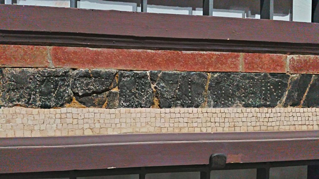 VII.7.32 Pompeii.
Detail of red and green/black floor mosaic with (part of the) epigraph, on display in Naples Archaeological Museum, inv. 113398.
Photo courtesy of Giuseppe Ciaramella, June 2017.