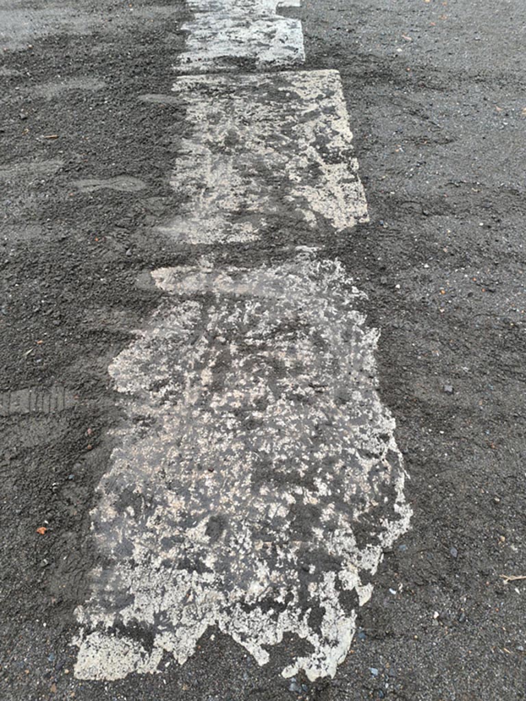 VII.8.00 Pompeii. May 2024.
Row of limestone slabs on east side of Forum, looking west from north end of portico of Eumachia’s Building.
Photo courtesy of Klaus Heese.
(Note – the letter L could not be securely identified. See VII.8.00, West side of Forum, for the letter Q.)
