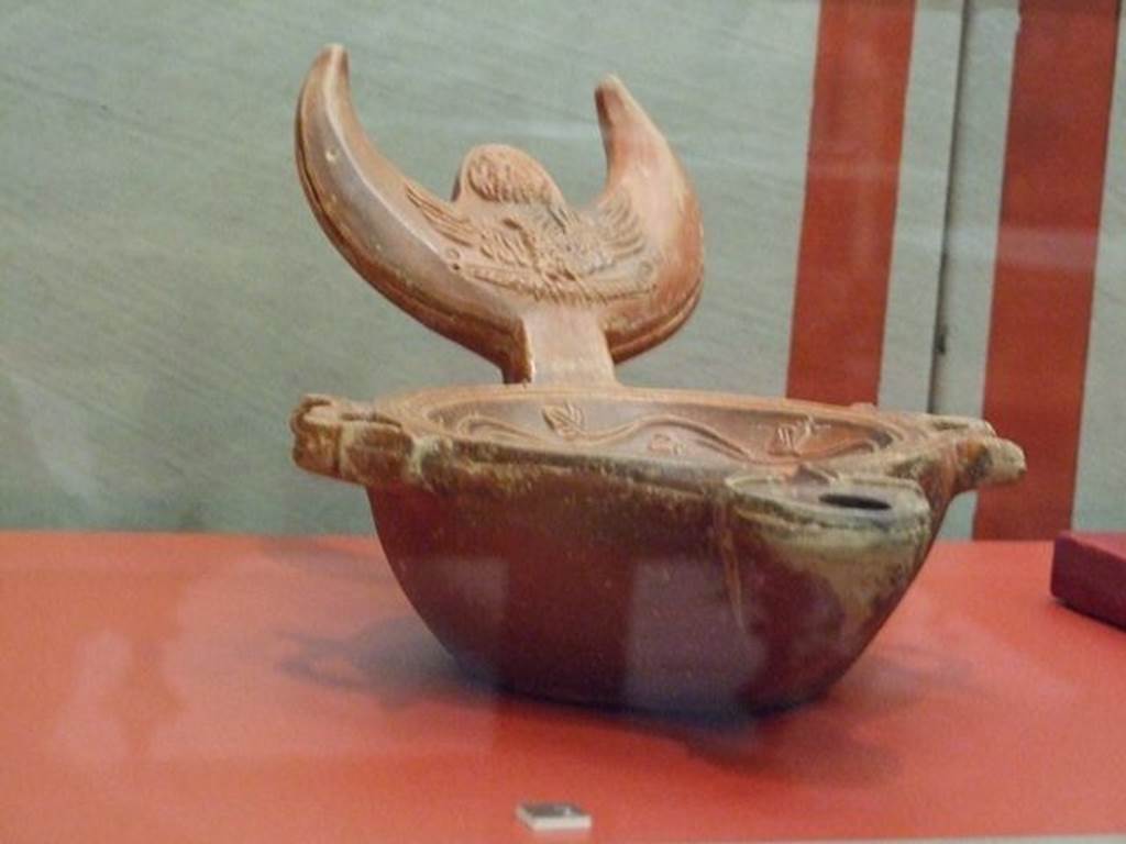 VI.16.19 Pompeii. Terracotta triple lamp with a crescent moon handle. The handle is decorated with the head of Jupiter Ammon and an eagle. SAP 13961. Photographed at “A Day in Pompeii” exhibition at Melbourne Museum. September 2009.