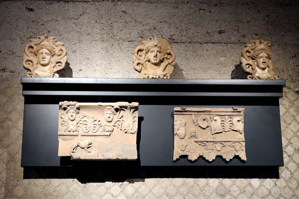 VIII.7.31 Pompeii. February 2021. Terracotta from Doric Temple.
Top: Part of a roof (sima) decorated with female faces alternating with palmettes. 
Lower left: decorative elements of the roof (antefixes) with the head of Athena and Hercules.
Lower right: Roof tiles decorated with sphinxes and vegetal motifs.
Photographed in the Antiquarium. Photo courtesy of Fabien Bièvre-Perrin (CC BY-NC-SA).
