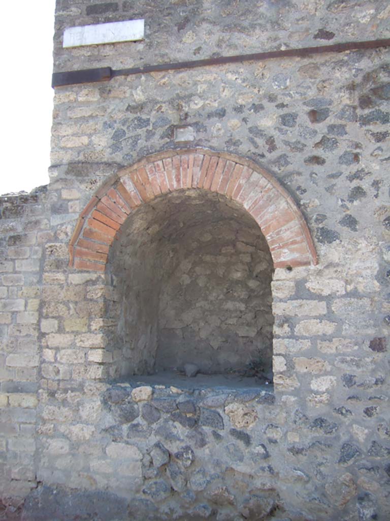 Pompeii II.4.7a. September 2005. Street shrine at east end of II.4 on Via dell’Abbondanza.
According to Van der Poel, this great niche, which was used as a compitum, was discovered by Spinazzola in 1912.
See Van der Poel, H. B., 1986. Corpus Topographicum Pompeianum, Part IIIA. Austin: University of Texas. (p. 46).
According to Della Corte in NdS – 
“Entirely excavated was an important public shrine fronting the roadway, and resulting in a rounded arched niche, 1.22m high; 1.06m wide; 1.08m deep, adorned above by a beautiful, raised stucco cornice. The niche which opened onto the pavement at the height of the breast of a man, was, as seems certain, a small temple in which the Penates and the protecting Divinity of Pompeii were worshipped.” 
See Notizie degli Scavi di Antichità, 1912, (p.68). 
