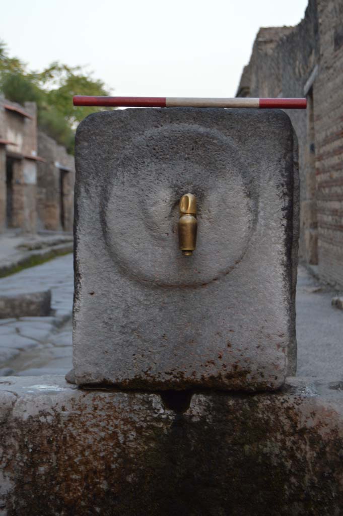 Fountain outside I.9.1 on Via dell Abbondanza. October 2018. 
Fountain head with relief of patera or plate on pilaster
Foto Taylor Lauritsen, ERC Grant 681269 DCOR.
