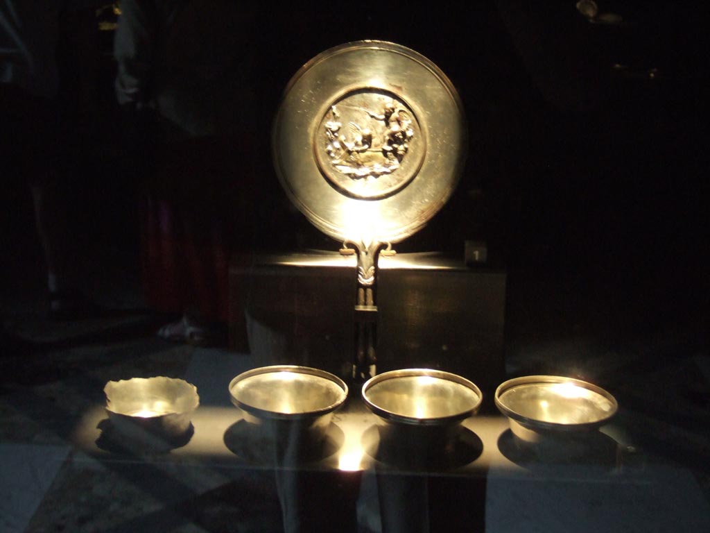 Silver found at Porta di Sarno on 3rd November 1959, together with a victim of the eruption and 61 gold coins and 51 silver coins. 
Silver mirror with two-pronged handle. The back has a scene in relief. 
This includes two cupids fishing, a boat with a dolphin emblem and at the side is an anchor and a small statue of Priapus
Now in Naples Archaeological Museum.  Inventory number 12607.
Four circular silver cups. Three are complete, inventory numbers 161581, 161582 and 161583.
The fourth is damaged, inventory number 161584.
See De Carolis E., in Guzzo, P. (A cura di), 2006. Argenti a Pompei. Milano, Electa. (p. 156).
