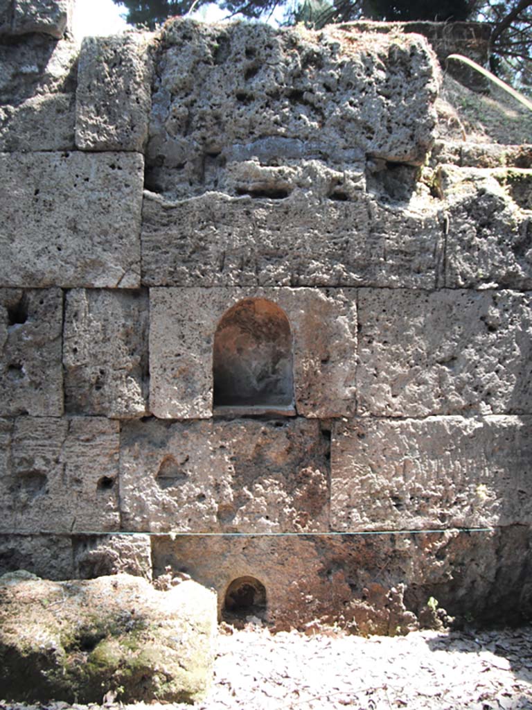 Porta Stabia, Pompeii. May 2011. East side, wall with two niches. Photo courtesy of Ivo van der Graaff.
According to Van der Graaff –
“Minerva was also present at the Porta Stabia (see Fig.8.2).
The gate still carries two small niches carved into the eastern wall of the court, meant to evoke a deity protecting the walls as well as travellers traversing the liminal space (Note 9).
At the time of their discovery, the upper niche retained traces of plaster coating with a graffito on the back wall that read PATRVA, a reference to Minerva Patrua (Note 10). ………………………
The lower niche belonged to a shrine in the first version of the gate, which saw the addition of an altar in the second phase.
In a third phase, workers partially buried the altar after raising the sidewalk in the late second or early first century BCE (Note 11).
A new sidewalk laid in the first century BCE completely buried the altar.
It was at that time that workers must have cut the second larger and higher niche, in an effort to maintain a continuity of cult.”
See Van der Graaff, I. (2018). The Fortifications of Pompeii and Ancient Italy. Routledge, (p.207).