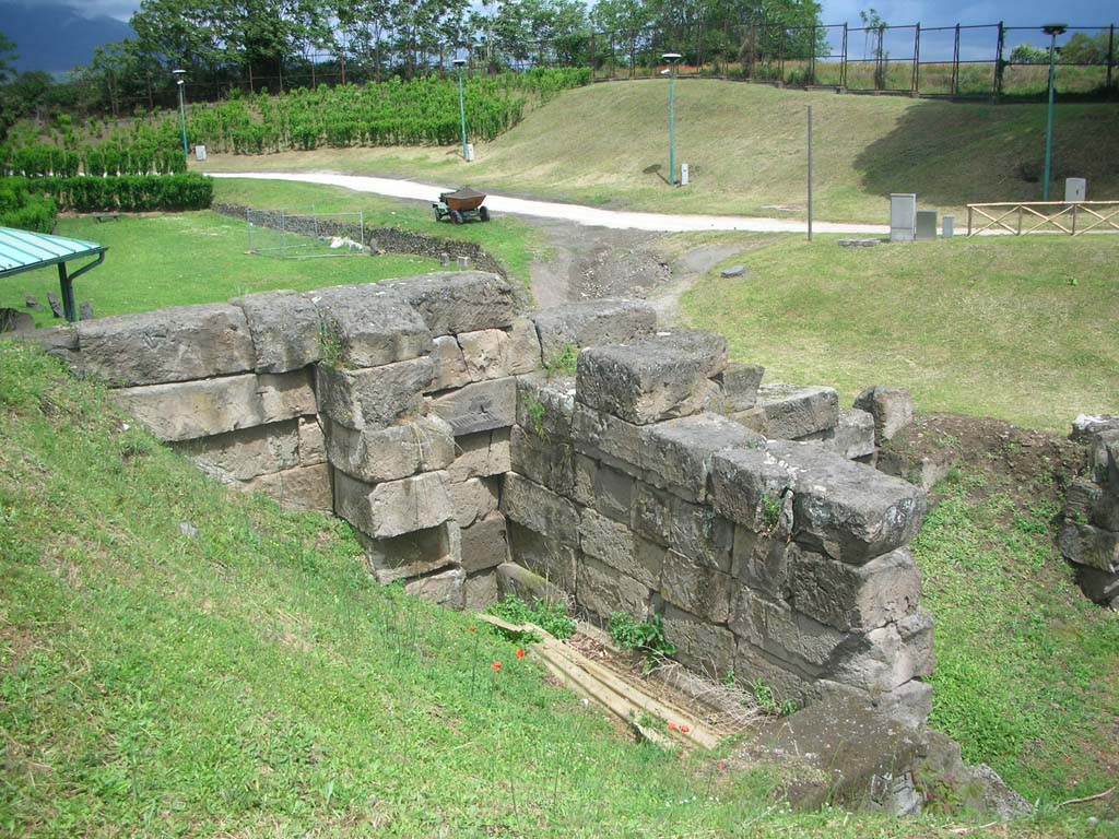 Vesuvian Gate Pompeii. May 2010. Looking north-east from upper area. Photo courtesy of Ivo van der Graaff.
According to Van der Graaff –
“The ornamental emphasis placed on the earliest gates finds a slight variation at the Porta Vesuvio because of its design (see Fig. 3.4).
Its bastions are set slightly aback from the outer curtain.
This layout created a double bastion on either side of the entrance – a circumstance undoubtedly related to its location in a weak area of the defences.
The gate was particularly vulnerable to attack because of its position on a natural downward slope in the terrain.
In an effort to strengthen the opening, engineers transformed the northwest tip of the gate into a tower. Today its remains are not immediately evident.
The southern and western facades are buried in the later agger, whereas the northern and eastern flanks are flush with the curtain wall.
Steps recovered in its southern side offered access to the building in its first phase.
The remains represent the only trace of a tower in the first Samnite circuit. Workers probably demolished it after the construction of Tower X slightly further west.”
See Van der Graaff, I. (2018). The Fortifications of Pompeii and Ancient Italy. Routledge, (p.54 and Fig. 3.4).