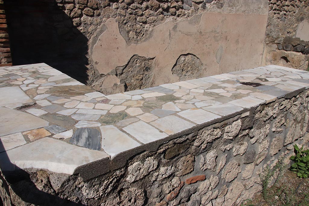 I.2.13 Pompeii. October 2024. Looking north-east across serving counter, towards north wall. Photo courtesy of Klaus Heese.