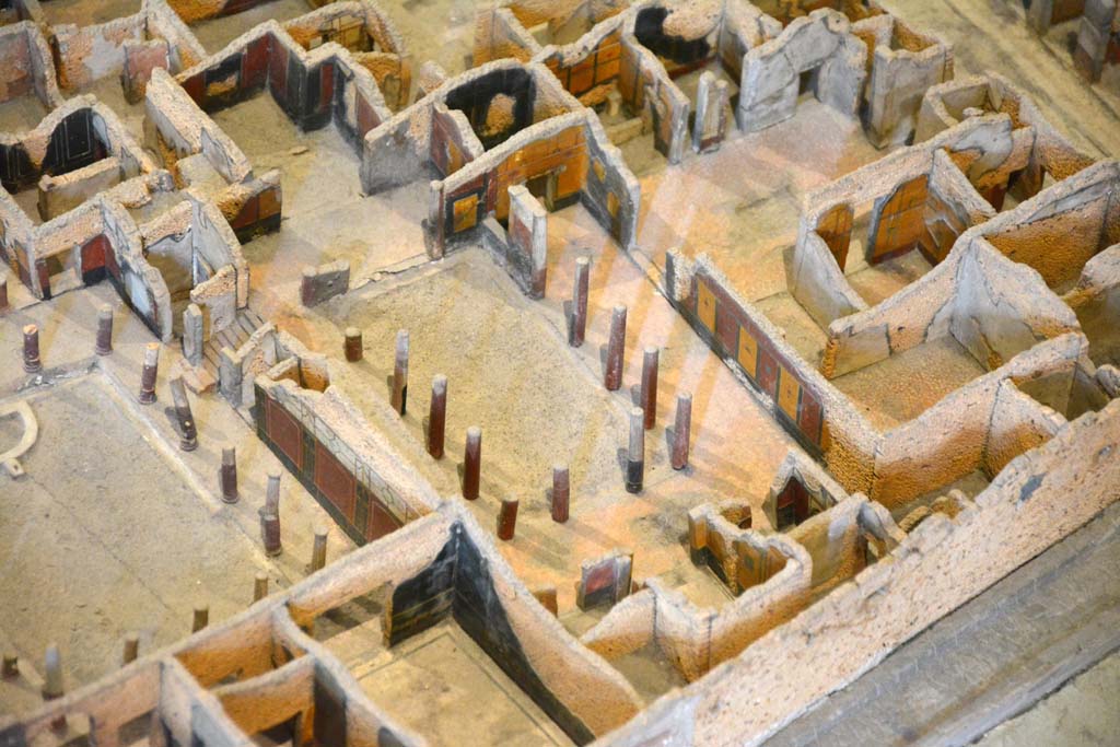 I.4.25 Pompeii. May 2019. Detail from model in Naples Archaeological Museum. 
Looking north-east across upper peristyle 56, in centre, towards open doorway into atrium 47, and through to entrance on Via dellAbbondanza, centre top.
Foto Tobias Busen, ERC Grant 681269 DCOR.

According to Jashemski 
The north (Upper) peristyle garden, which belonged originally to a house whose entrance was on the Via dellAbbondanza, was reached by a flight of steps from the central (Middle) peristyle which lies on a level about two metres below. This (Upper) garden was surrounded by a portico on the south, east and most of the north sides. There was a travertine puteal between the two middle columns on the east side. On the west, a large exedra (room 57), preceded by a vestibule, had a splendid view of the garden, as did the triclinium (room 58) on the east. The columns, like those in the central peristyle, were made of brick and Sarno limestone and faced with stucco. The columns, with the exception of those opposite the entrances of the large exedra, the triclinium, and to the atrium on the north, were left unfluted. There was a gutter around the edges of the garden.
See Jashemski, W. F., 1993. The Gardens of Pompeii, Volume II: Appendices. New York: Caratzas. (p.31-32).
