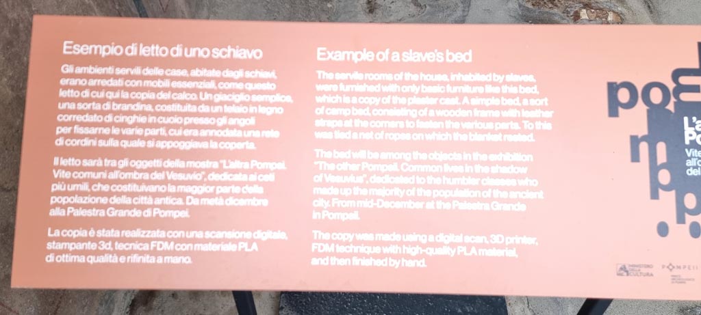 I.6.3 Pompeii. December 2023. 
Description card, for cot/bed on display in I.6.3 but from the suburban villa of Civita Giuliana. 
The cot will be displayed in an exhibition in the Palaestra from December 2023 to December 2024, entitled “The other Pompeii: Common lives in the shadow of Vesuvius.” 
Photo courtesy of Miriam Colomer.
