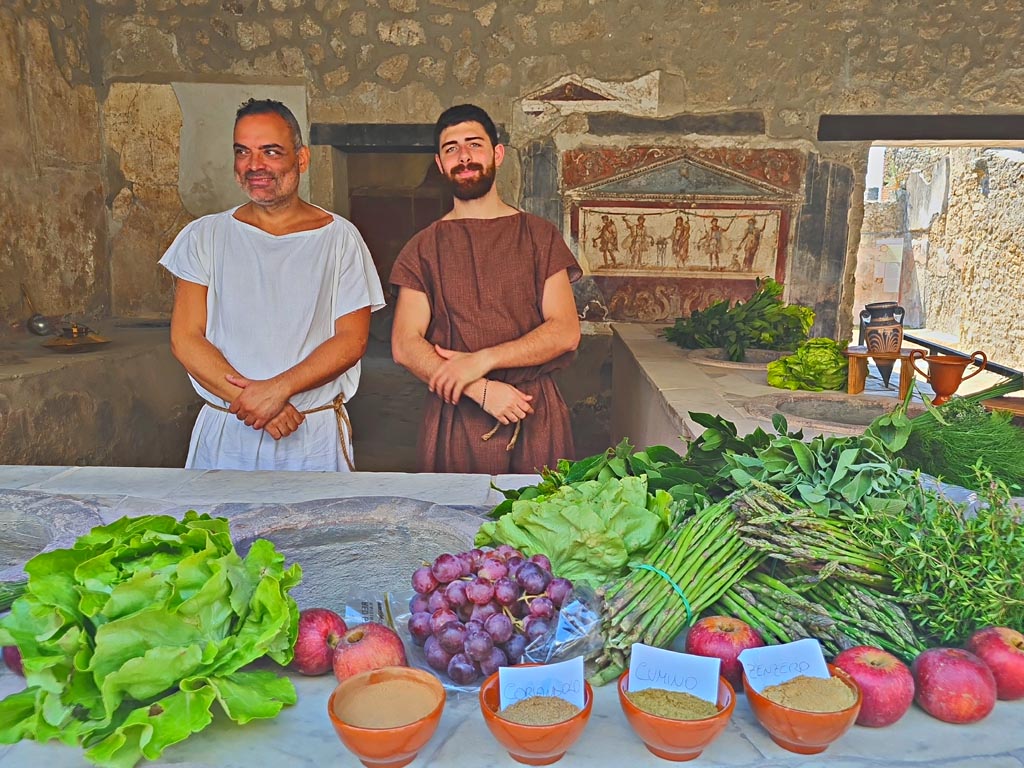 I.8.8 Pompeii. 8th June 2024. 
Looking south across fully-loaded counter towards actors playing part of welcoming ancient pompeians, waiting to greet customers.
Photo courtesy of Giuseppe Ciaramella.
Historical reconstruction entitled L’altra Pompei prende vita (The other Pompeii comes to life).
