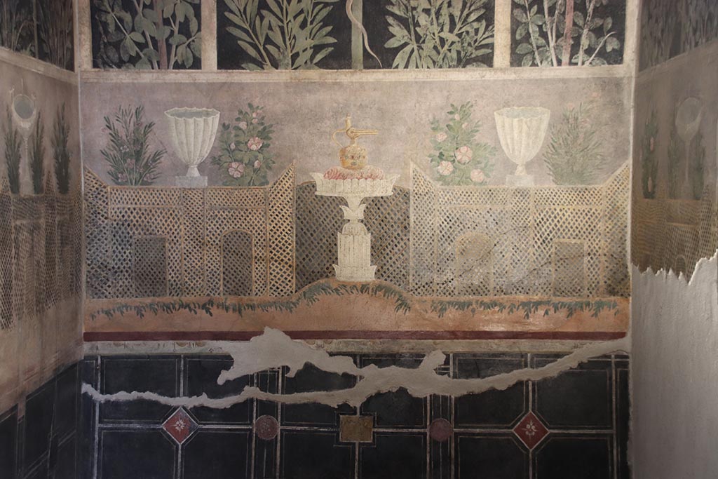 I.9.5 Pompeii. October 2024. Room 11, detail from lower east wall of cubiculum. 
Garden painting with lattice fencing, white vases and table with Isis jug or jar. Photo courtesy of Klaus Heese
