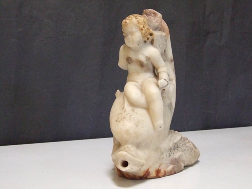 I.9.14 Pompeii. Marble fountain statuette. Amorino with basket on arm riding on dolphin. SAP inventory number 8127. Found in 1951.