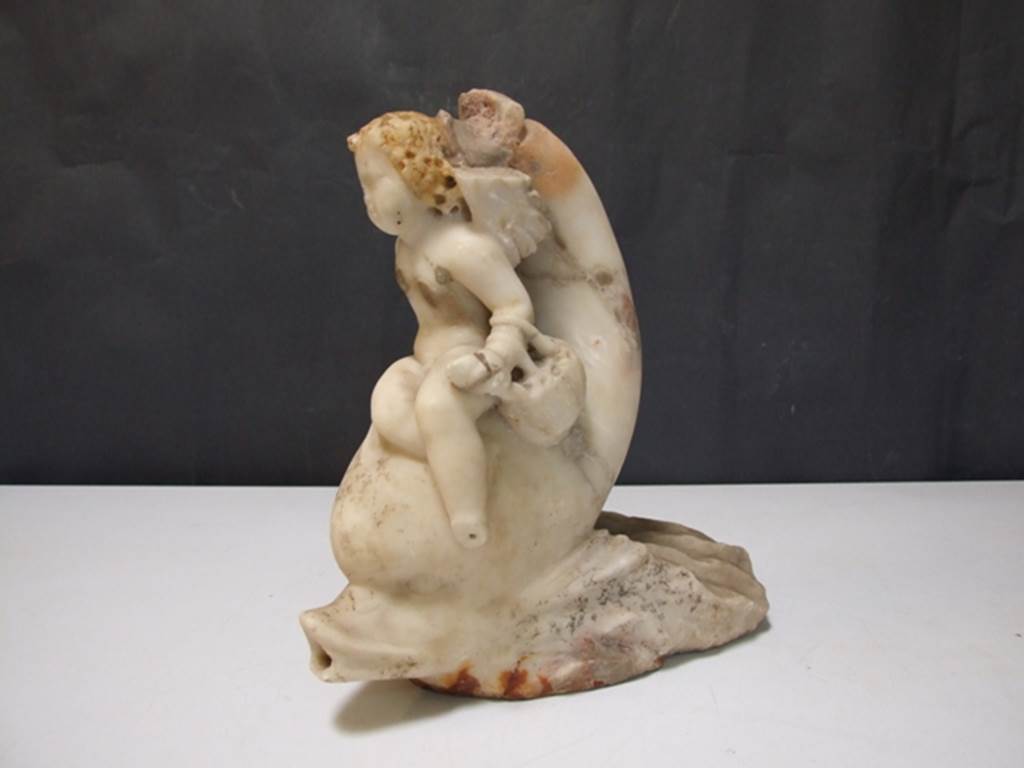 I.9.14 Pompeii. Marble fountain statuette. Amorino with basket on arm riding on dolphin. SAP inventory number 8127. Found in 1951.