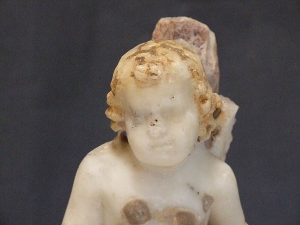 I.9.14 Pompeii. Marble fountain statuette. Amorino with basket on arm riding on dolphin. Head of Amorini. SAP inventory number 8127. Found in 1951.