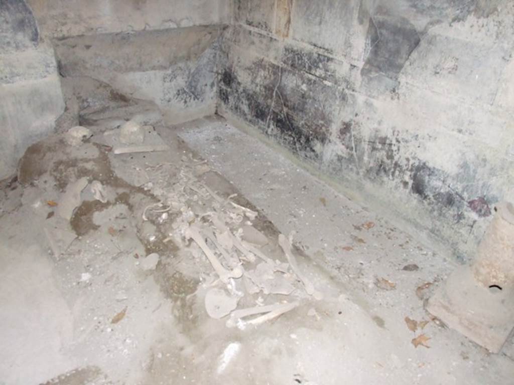 I.10.7 Pompeii. March 2009. Room 12, north-west corner of triclinium, with remains of skeletons. According to Civale, in the triclinium two people had sought refuge: an adult who was discovered on the floor, his arms clutching the edge of a dining couch, and a second, younger victim his arms folded under the head and legs stretched out on the floor.  
On the ground between the adults feet, lay a little cloth bag containing a small hoard of 26 silver coins, amounting to just 104 sesterces.  
In the triclinium, another little heap of 48 coins was found, perhaps also the savings of one of the victims. See Guzzo, P.G. ed. (2003): Tales from an eruption  (Civale, A: The House of the Craftsman). Milan, Electa; (p.140-41)
