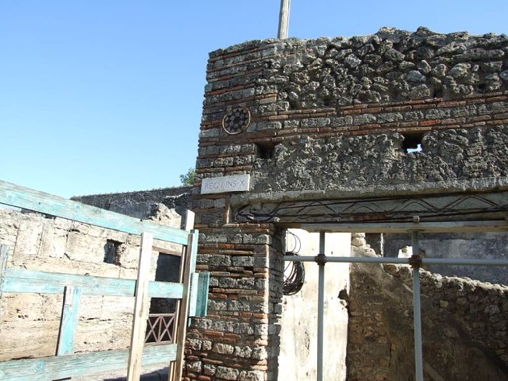 I.10.9 Pompeii. March 2009. Coloured terracotta decorated circular plaque on north side of entrance. 
According to NdS, 
a little above the architrave of the doorway, were four large holes (two of them can be seen in the above photo), and a row of smaller ones indicating the presence of a canopy originally.
See Notizie degli Scavi, 1934, (p.321)
