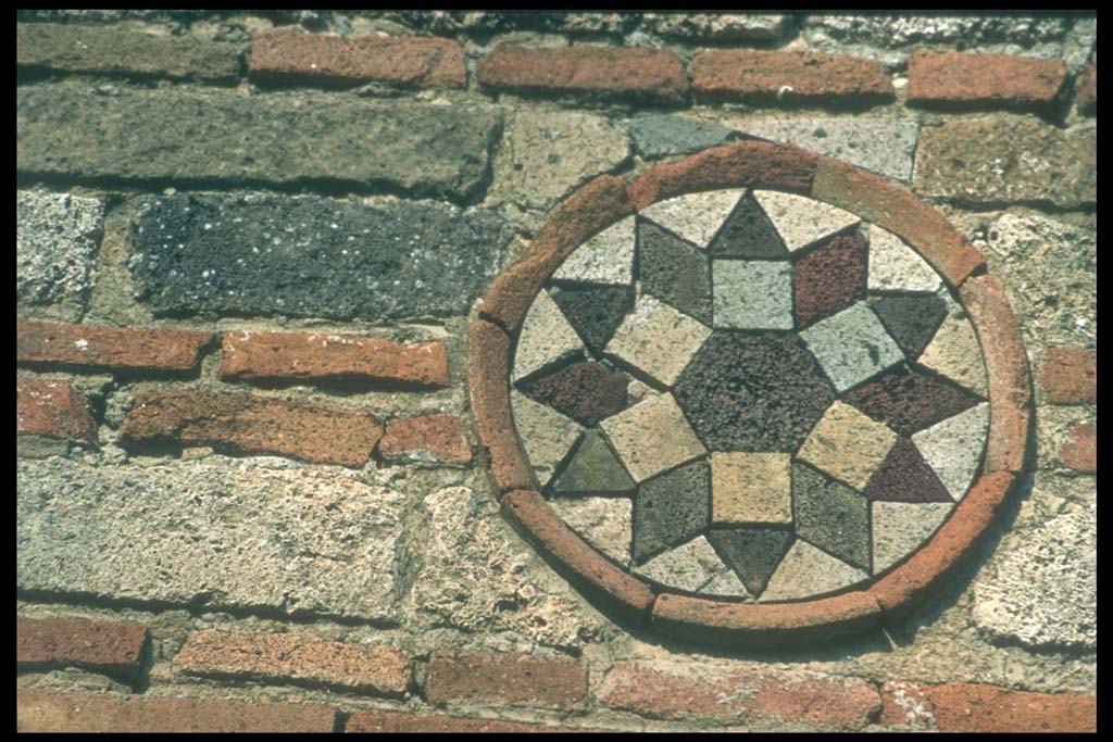 I.10.9 Pompeii. Coloured terracotta decorated circular plaque on north side of entrance. 
Photographed 1970-79 by Günther Einhorn, picture courtesy of his son Ralf Einhorn.
