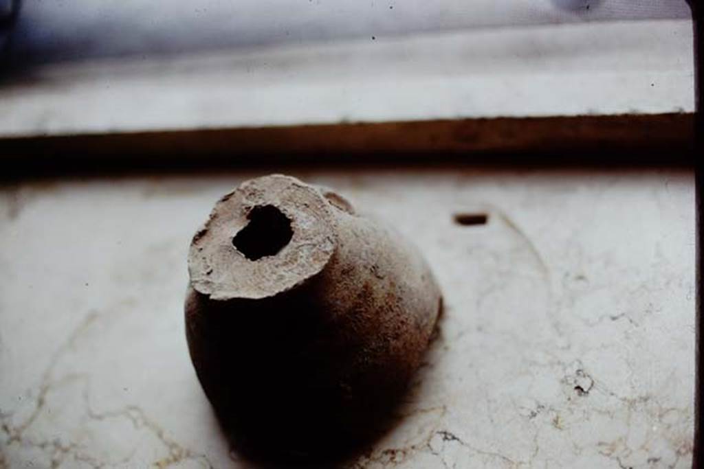 I.14.2 Pompeii. 1972. Planting pot with hole in the bottom. According to Wilhelmina, 
Fragments of planting pots (which had been badly damaged during the original excavation of this site) were found along the north wall. These may have indicated that a few grafted trees of a special variety might have been started in these pots. 
Photo by Stanley A. Jashemski. 
Source: The Wilhelmina and Stanley A. Jashemski archive in the University of Maryland Library, Special Collections (See collection page) and made available under the Creative Commons Attribution-Non Commercial License v.4. See Licence and use details. J72f0729
