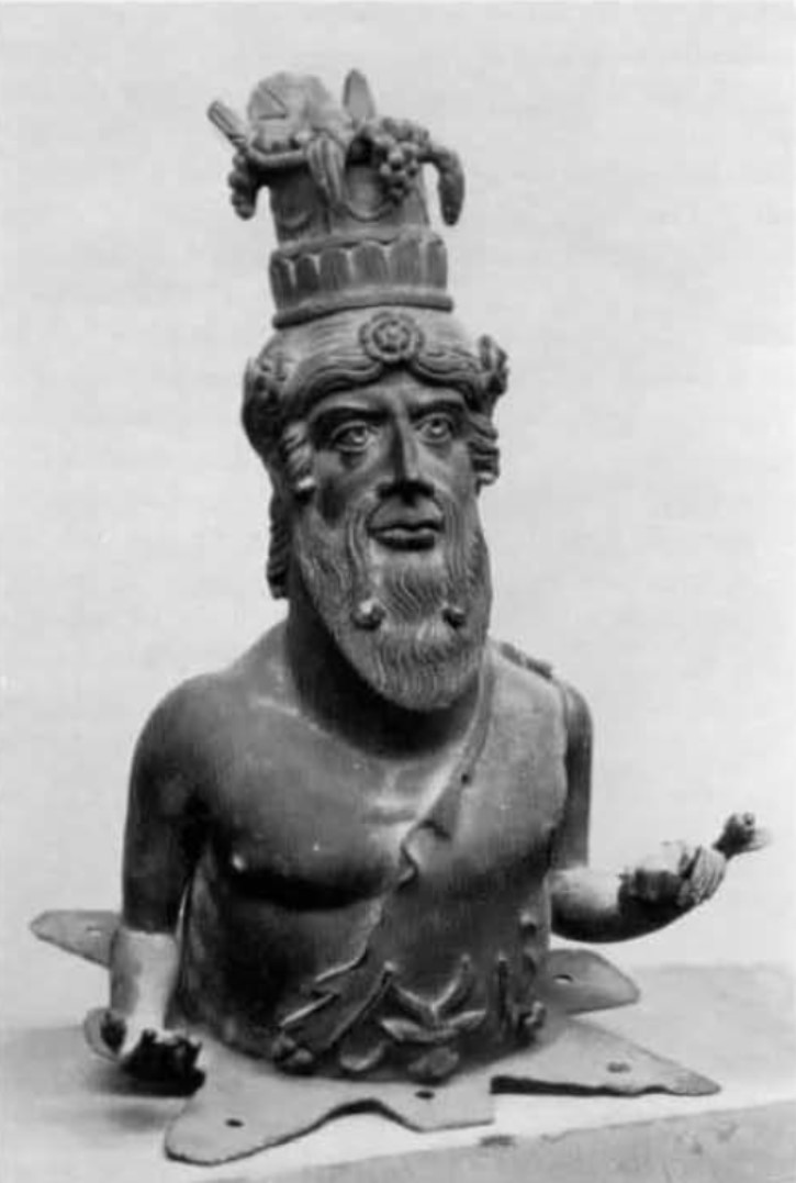 I.16.5 Pompeii. Found on 26th September 1957 in a cubiculum on the south side of the atrium
Small bronze representing a bearded male, with his arms stretched forward and his hands outstretched.
In his left hand holding the stem of a poppy in bud with its leaves, while the right hand, left without its attribute, shows his empty palm.
The figure was detached just above the waist-line and laid on a thin bronze plate, cut out into an eight-pointed star scheme; of these tips, four are arranged diagonally and are sharp, and the other four, interspersed with these, are blunt and with rounded edges.
This was found, with many other bronzes, near to the wooden parts of an armarium. 
Parco Archeologico di Pompeii. Inventory number 11471.
See Elia, O. Bacco Fanciullo e Dioniso Chtonio a Pompei. Bollettino d'Arte 1961, Fasc. I-II, (p.4, figs.5-6).
