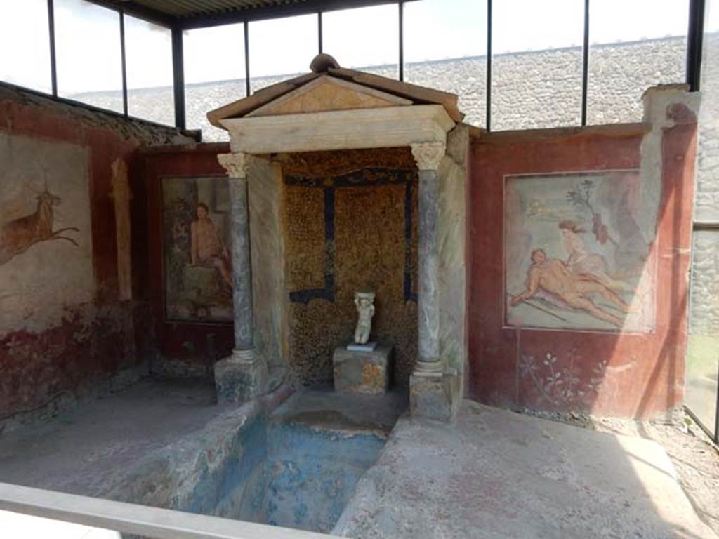 II.2.2 Pompeii. May 2016. Room “k”, summer dining room with biclinium and water feature.
Photo courtesy of Buzz Ferebee.
According to Soprano –
Ubicazione: braccio trasversale dell’euripus. L. summus, m.3.40; l. imus, m.2.78.
Bibliog. Maiuri, Pompei, p.93; idem L’ultima fase edilizia di Pompei (Istituto di Studi Romani, Roma, 1942), p.152 e tav.xlviii;
Maiuri-Pane, Monumenti italiani editi a cura dell’Accad. dei Lincei, serie II, fasc. I, La Casa di Loreio Tiburtino e la Villa di Diomede, p.6 e tav. ii con pianta e sezione;
Della Corte,in “Atti del II Congresso dell’Istituto di Studi Romani”, I, p.19;
I MM Tiburtini di Pompei, in ”Atti e Memorie della Societa Tiburtina di Storia e Arte”, XI-XII, 1931, p.188; Pompei, i Nuovi Scavie l’Anfiteatro, p.66.

Ad est del braccio trasversale dell’euripus che adorna il giardino della casa, s’apre un ninfeo e, dinanzi, il bacino di una vasca rettangolare. 
Ai lati di esso si dispongono i due letti tricliniari in muratura.
Il l. summus era addossato al muro con due lati mentre il l. imus, dista 60 cm. dal muro cui era addossato il ninfeo; le spondae (sponde esterne) di entrambi
i letti sono rialzate. I letti hanno un rivestimento in intonaco rosso, e su quello summus era l’indicazione “Lucius pinxit”, che ci tramanda la firma del pittore dei due dipinti a soggetto mitologico del ninfeo: Narciso al fonte e Piramo e Tisbe.
See Soprano, P. (1950). I triclini all’aperto di Pompei. (In Pompeiana, raccolta di studi per il secondo centenario degli scavi di Pompei. Napoli, Gaetano Macchiaroli, Editore, p.305-6, no.25 (wrongly numbered as I.5.2).

