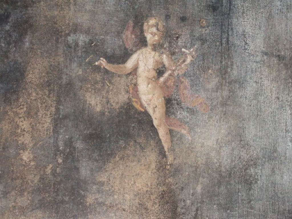 II.3.3 Pompeii. December 2005. Room 6, south wall of triclinium. 
Wall painting of Amorino or flying cupid holding a baetylus (or alabaster vase) in his left hand.



