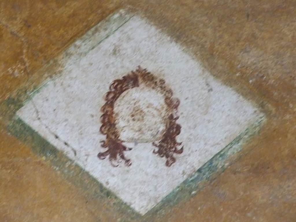 II.3.3 Pompeii. December 2006. Room 11, west portico. Diamond shaped wall painting of a face.