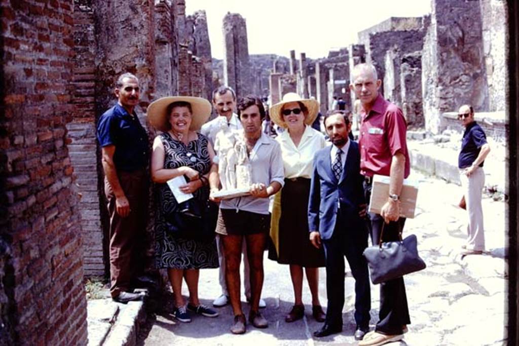 II.8.6 Pompeii, 1973. The statue of Hercules which was found in the lararium in his garden, being carried along the Via dellAbbondanza.
Photo by Stanley A. Jashemski. 
Source: The Wilhelmina and Stanley A. Jashemski archive in the University of Maryland Library, Special Collections (See collection page) and made available under the Creative Commons Attribution-Non Commercial License v.4. See Licence and use details.
J73f0610
According to Wilhelmina, 
Guiseppina Cerulli had agreed that Hercules could be returned to his garden for the final photos. He was triumphantly carried along the Via dellAbbondanza accompanied by admirers and placed again in his shrine. All of her workers wanted their pictures taken with him.
See Jashemski, W.F., 2014. Discovering the Gardens of Pompeii: Memoirs of a Garden Archaeologist, (p.207).
