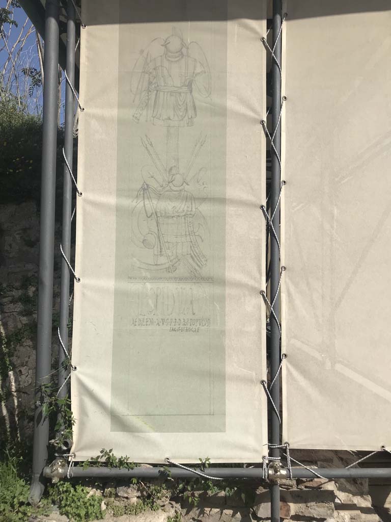 III.3.6 Pompeii. April 2019. West entrance pillar display notice.
Drawings, from 1930, of the large military trophies that decorated the pillars at the entrance of the Schola.
Photo courtesy of Rick Bauer.
