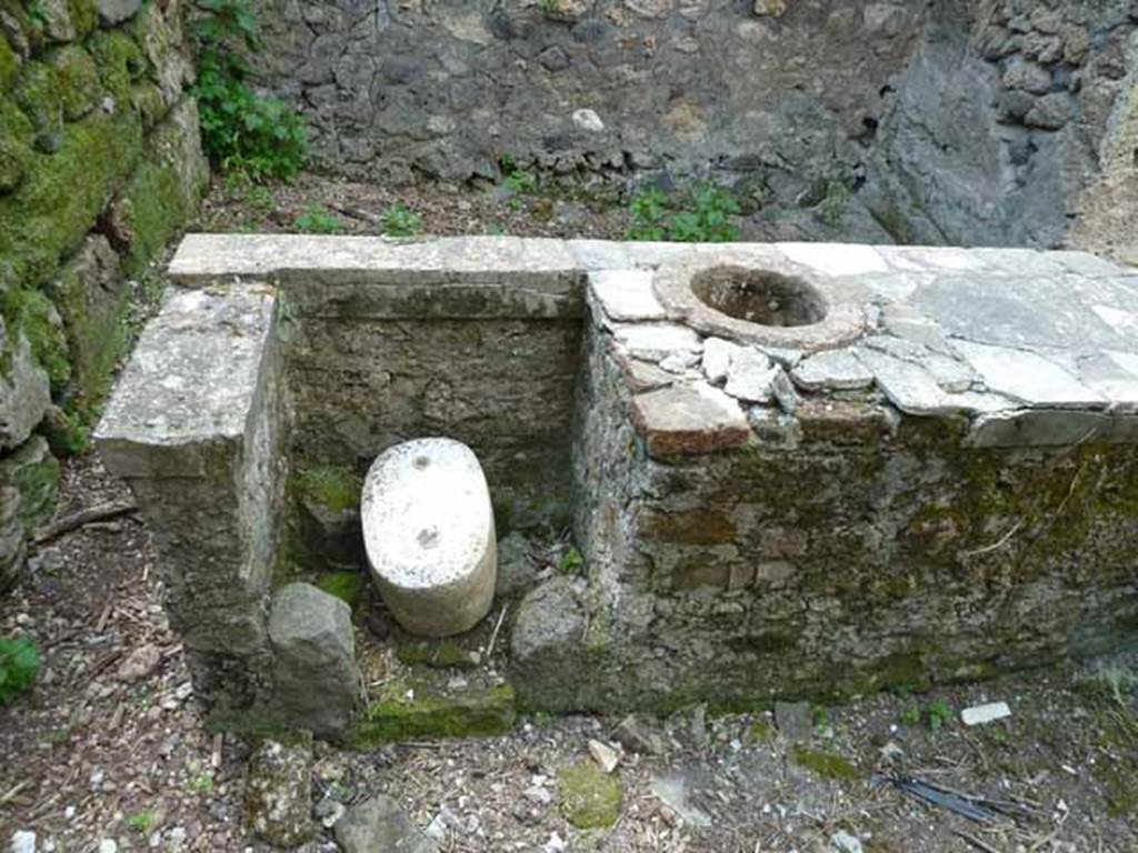 III.8.8 Pompeii. May 2010. Rear of counter, looking west. The remains of the hearth can be seen on the left, and one embedded urn on the right. 
