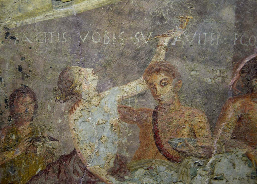 V.2.4 Pompeii. June 2017. 
Room 15, detail from west end of the painting of banqueting scene from north wall of triclinium. Photo courtesy of Johannes Eber.
According to the Epigraphik-Datenbank Clauss/Slaby (See www.manfredclauss.de), this reads:
Facitis vobis suaviter ego canto   [CIL IV 3442a]

