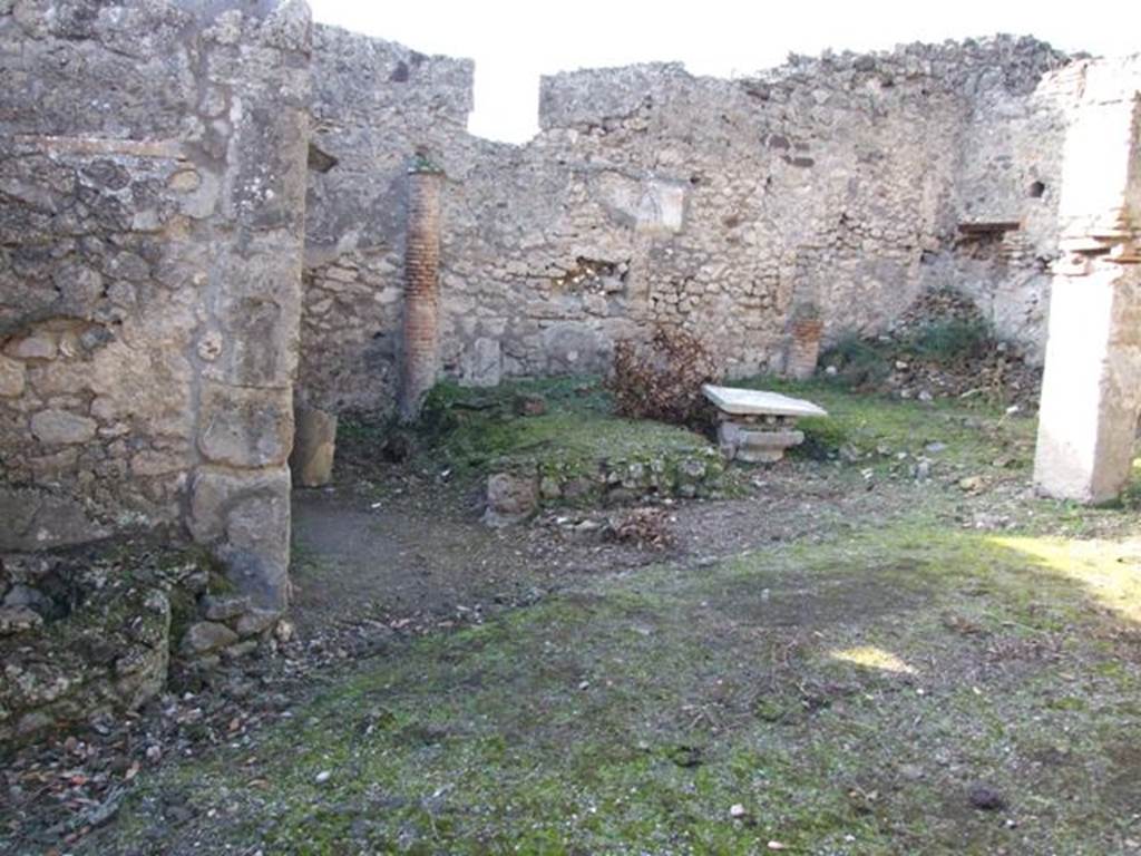 V.2.15 Pompeii. December 2007. Peristyle, looking west at remains of triclinium.
According to Jashemski 
There was a narrow portico on the east supported by three columns which were joined by a low wall; the wider portico on the north in addition to the corner column was supported by a pillar. Between the corner column and the pillar stood a rectangular marble table mounted on two supports.
On the west, the garden was enclosed by a low wall which was shaped to leave room for the cistern-opening in the south-west corner. 
There was a gutter along the outer edge of the garden.
Built against the west wall was a masonry triclinium (l. medius, 4.20m; l . imus and l. summus, 3.30m; a rectangular table between the couches 0.93 x 0.57m).
It was shaded by a pergola supported by two columns in front, two engaged columns at the rear. 
The columns were covered in yellow stucco on which vines were painted. 
The holes in which the little poles which supported the vines were inserted are still visible.
See Jashemski, W. F., 1993. The Gardens of Pompeii, Volume II: Appendices. New York: Caratzas. (p.111).
